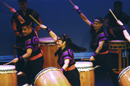 San Jose Taiko members lift their arms in unison during a drum performance