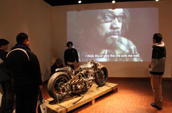 motorcycle in front of video playing on the wall