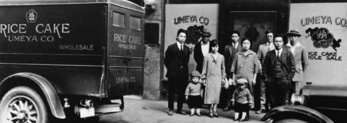 A family stands in front of a storefront that is labeled as "Umeya Co rice cake wholesale"