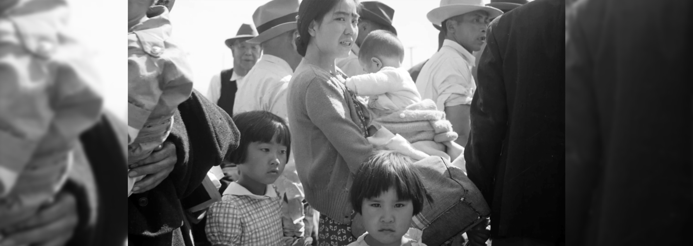 A black and white photo of children and a woman holding a baby in her arms.