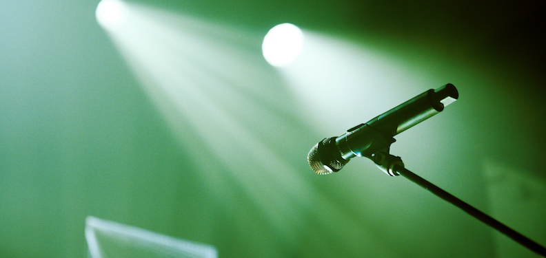 microphone on stage with spotlights on green background