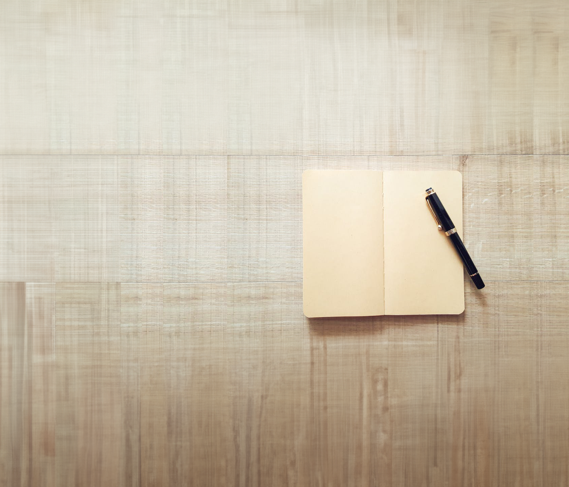 blank pages in open book and pen on tan textured cloth background