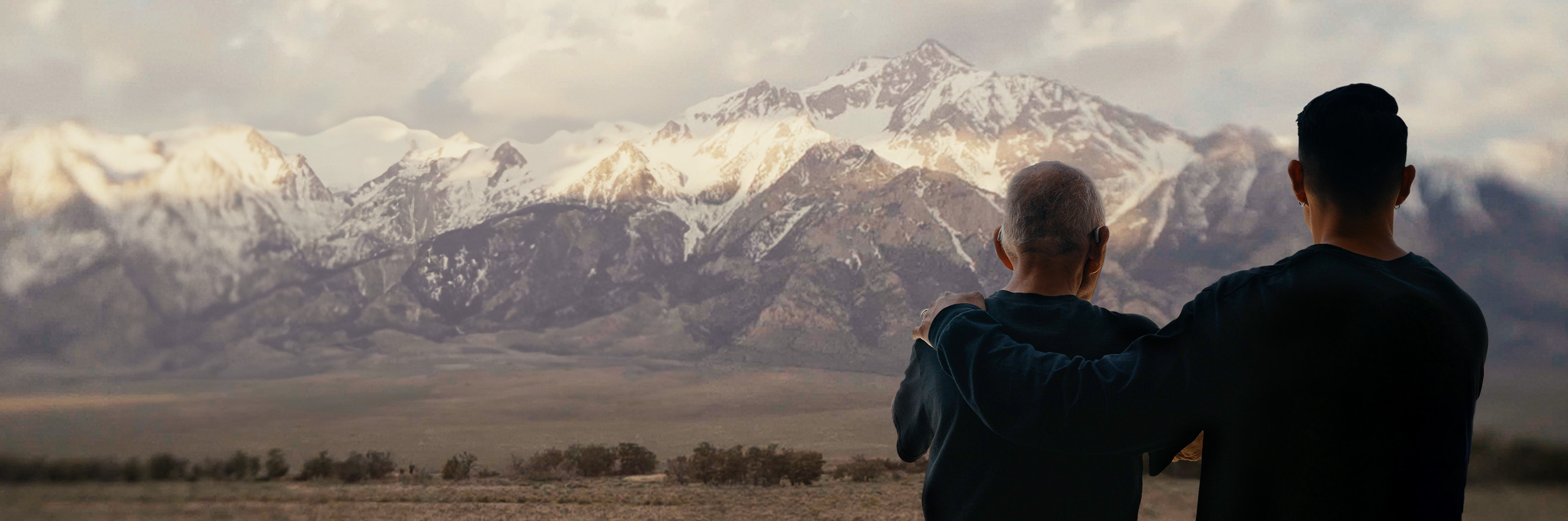 Robert Nakamura and son Tadashi Nakamura looking at snow capped mountains behind Manzanar