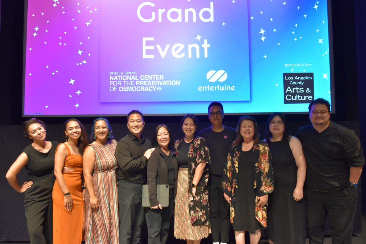 Group shot of actors in front on event title on screen