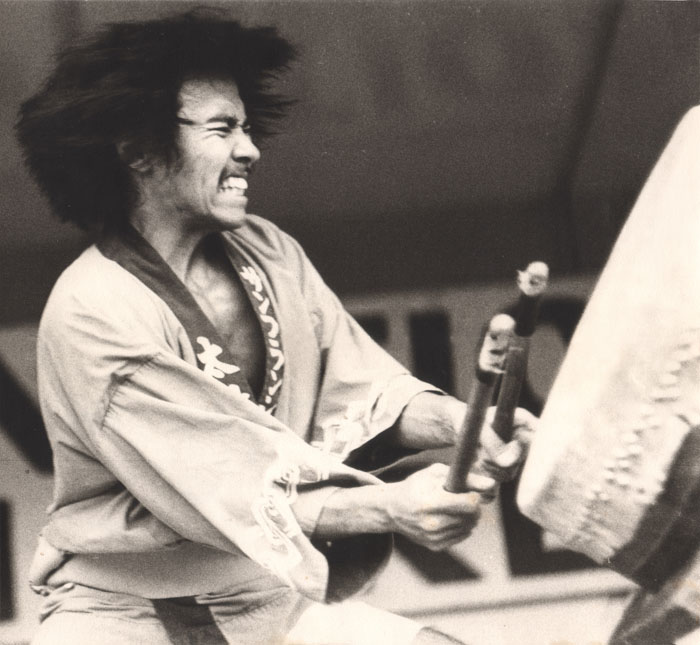 Black and white image of Kenny Endo as he plays the drum with vigor