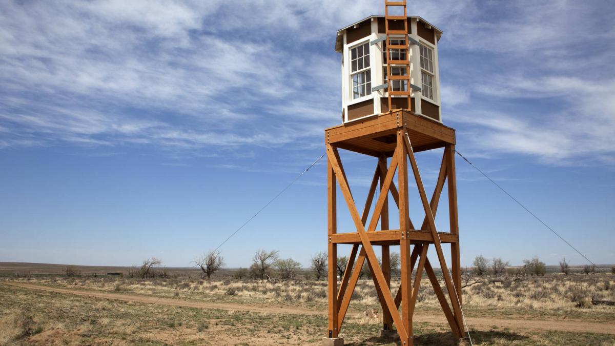 photo of guard tower at Amache concentration camp with horizon and cloudy sky in background.