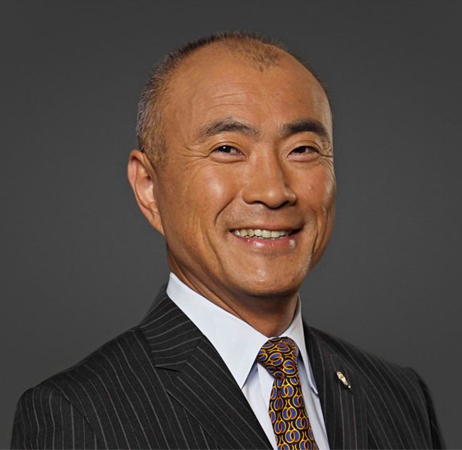 Toshizo Watanabe smiling and wearing a suit