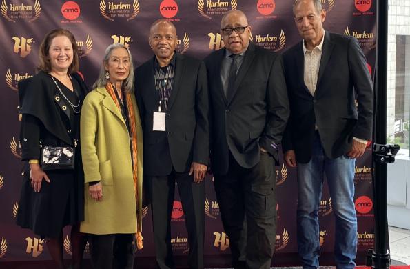 Five people stand in front of a step and repeat at a film festival