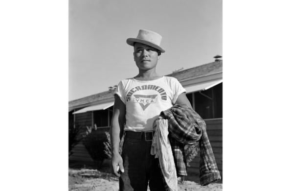 Man with hat holding flannel shirts in left arm