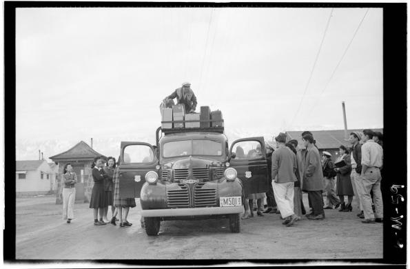 Japanese citizens stand around a car being packed up