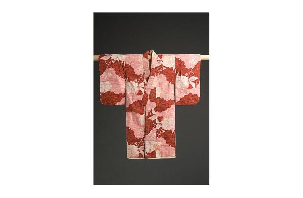 Child's kimono splayed out on a wooden rack. Hand sewn, pink, red, and white with sakura and wave design