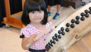 young girl drumming a taiko drum during a Natsumatsuri demonstration