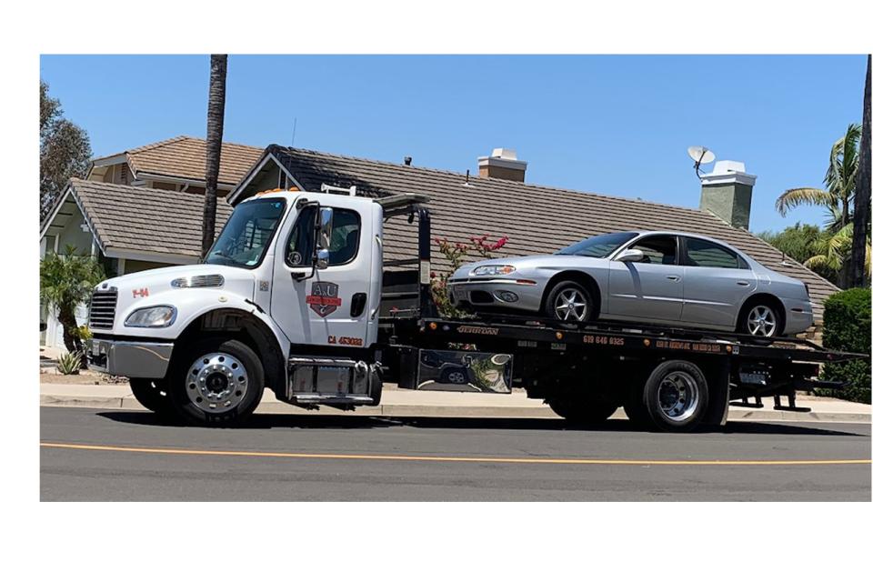 Tow truck hauling away a JANM car donation