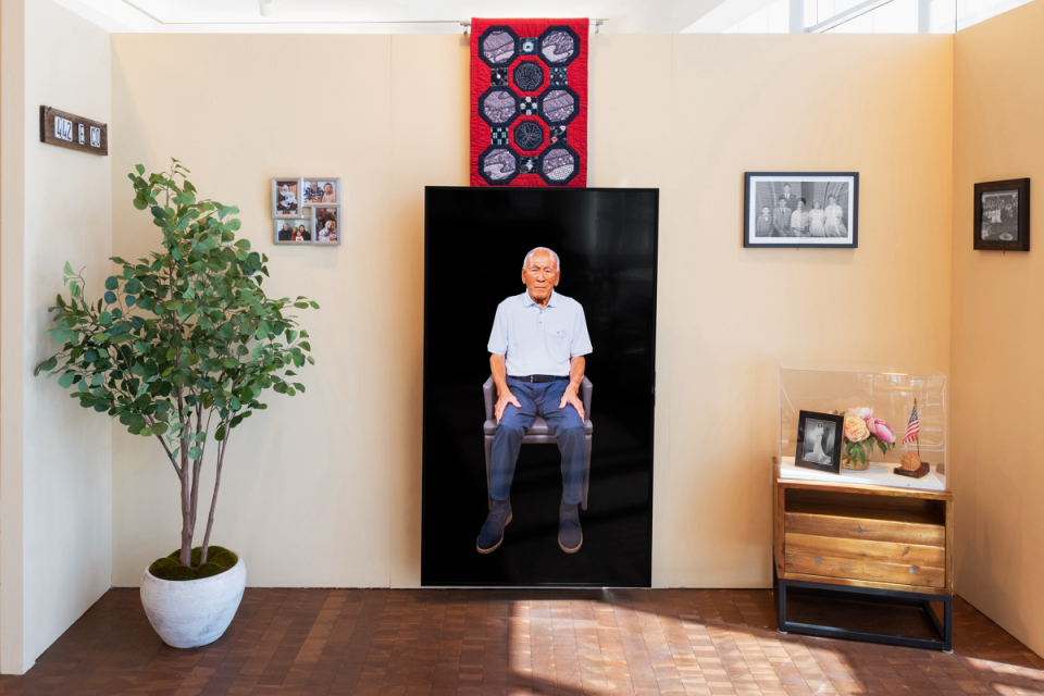 exhibition display with TV monitor in the center and framed wall hangings on each wall