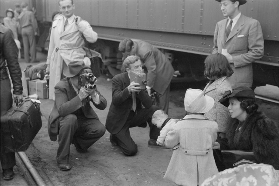 Two young girls being filmed as they wait to board a train that will take them to Manzanar