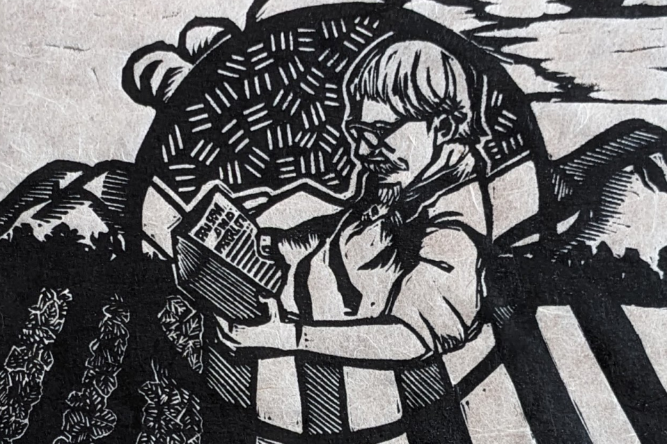 woodblock print of man reading a book with farm fields behind