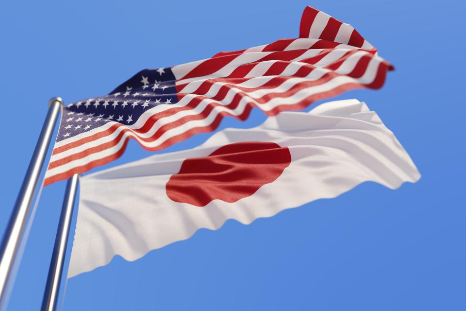 photo of United States flag and the Japan flag on separate poles blowing in the wind