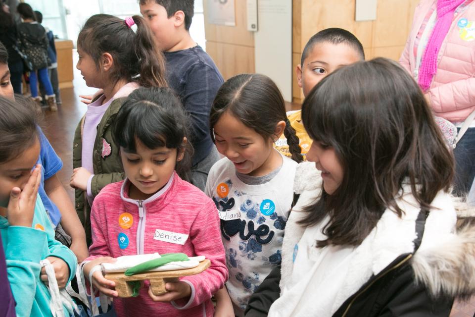 a group of school children interacting with a Japanese geta from the camps in the common ground exhibition