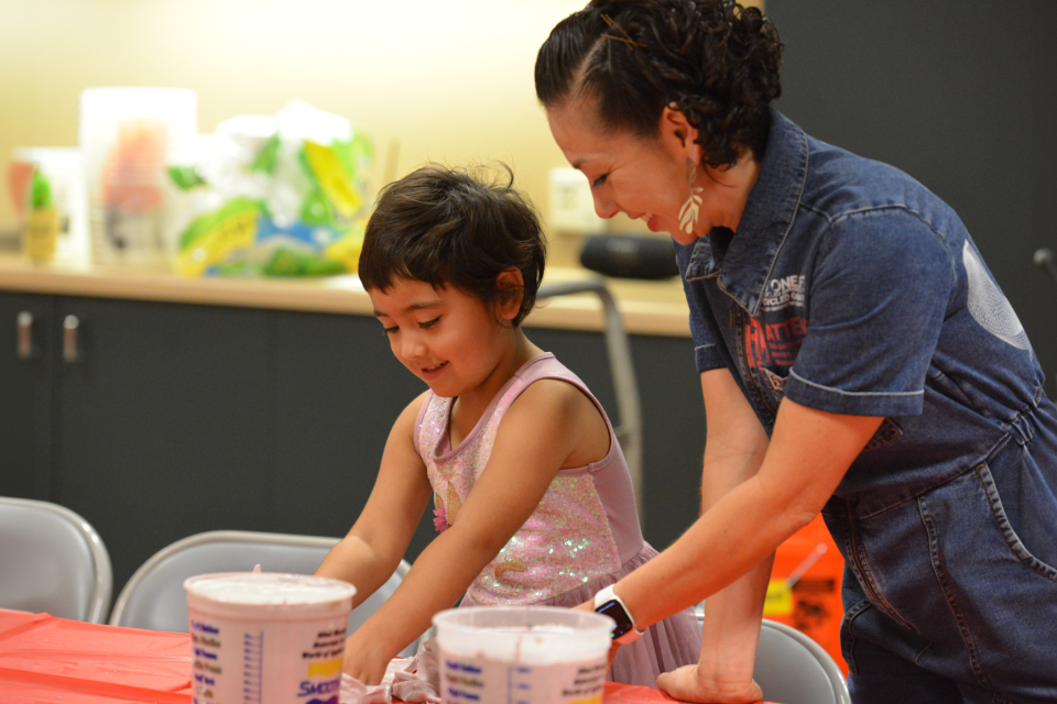 a little girl and adult make hand casts at a craft table