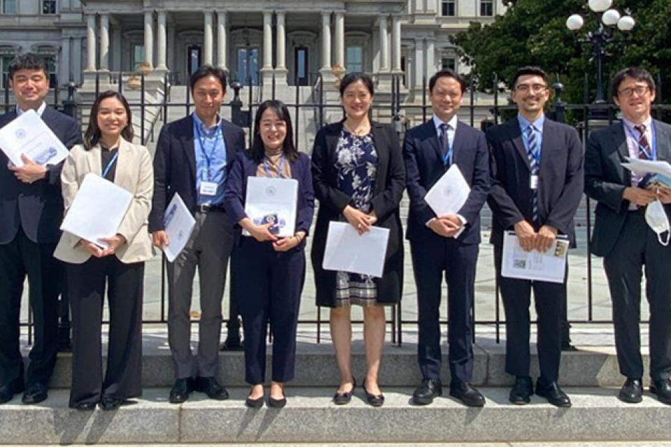 group photo of young adults standing in front of a historic building