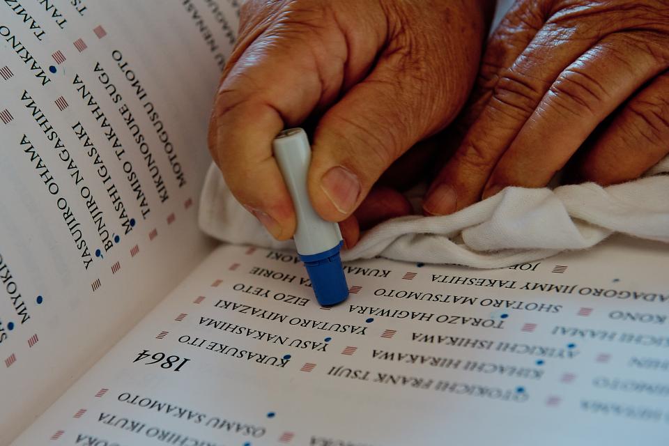 a person's hand stamping a dot under a name in a book