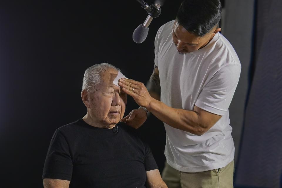 son wiping his elderly father's brow on set