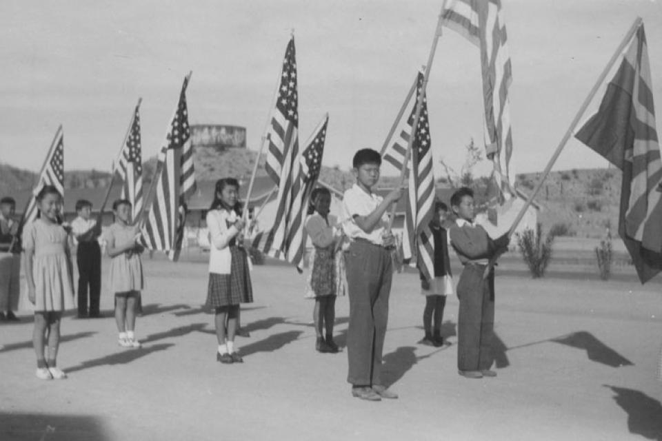 American School children hold American flags while in American concentration camp