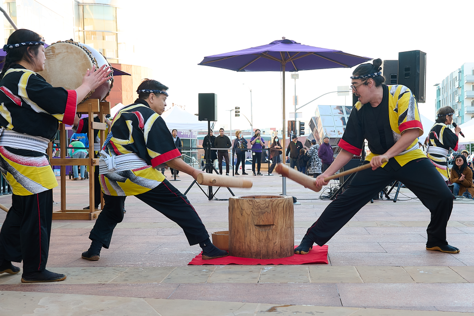 Taiko group pounding mochi at family festival in front of crowd