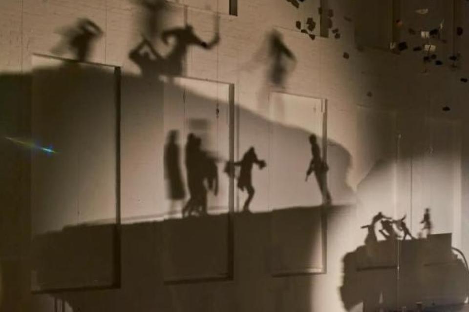 Moving shadows projected on wall of people protesting by artist Glen Kaino 