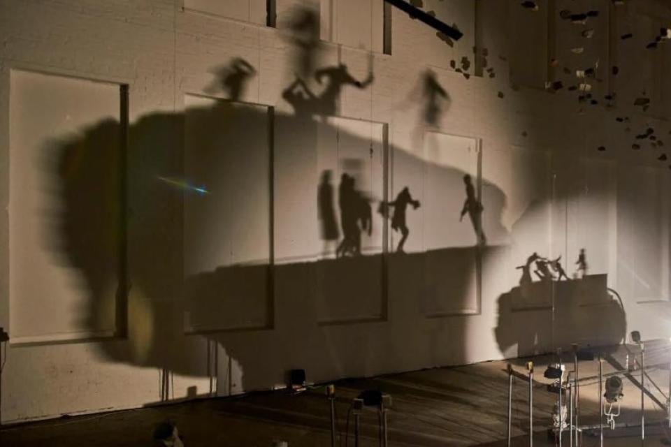 Moving shadows projected on wall of people protesting by artist Glen Kaino 