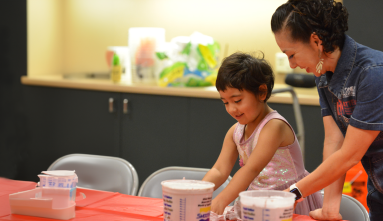 a little girl and adult make hand casts at a craft table